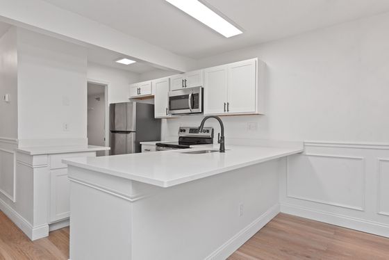Modern kitchen with sleek white cabinetry, stainless steel appliances, and a spacious quartz countertop, perfect for entertaining.