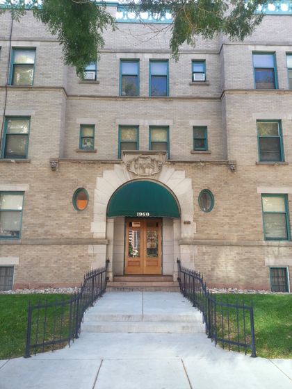 Elegant vintage apartment building with arched doorway and green awnings.