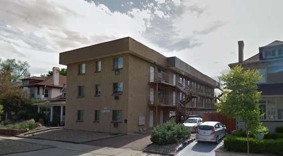 Street view of a three-story apartment building with parking, located in a charming neighborhood.