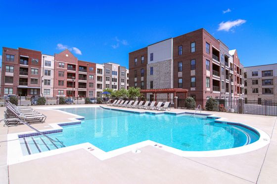 Modern apartment complex with sparkling outdoor pool and sun loungers.