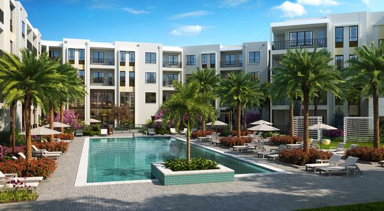 Elegant apartment complex with a central swimming pool surrounded by lush palm trees and sun loungers.