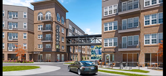 Modern apartment complex with brick facade, large windows, and a connecting skywalk.