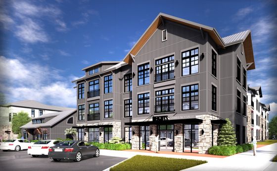 Charming modern apartment building with expansive windows, stone accents, and lush landscaping set against a clear blue sky.