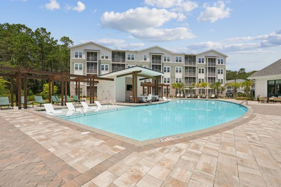 Luxurious apartment complex with a stunning pool, surrounded by elegant lounge areas and modern architecture.