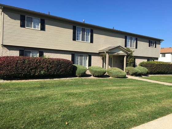Charming two-story apartment building with manicured landscaping and inviting entryway, perfect for modern living.