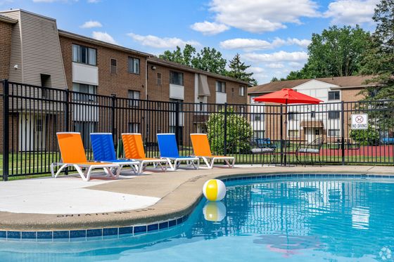 Inviting outdoor swimming pool area with colorful lounge chairs and vibrant umbrella, ideal for relaxation and leisure.