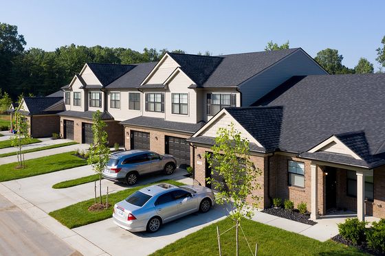 Charming row of modern townhouses with brick facades, surrounded by lush greenery and featuring convenient garage parking.