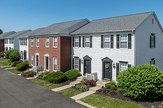 Charming row of townhouses with classic brick and siding exteriors, featuring tidy landscaping and inviting entrances.