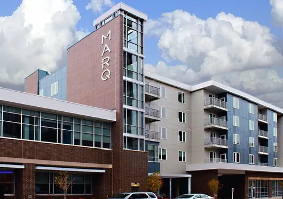 Contemporary apartment building with modern design, featuring glass balconies and stylish architecture under a stunning cloudy sky.