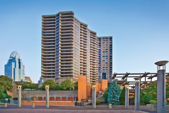 Modern urban high-rise apartment complex surrounded by lush greenery and contemporary architecture, offering stunning city views.