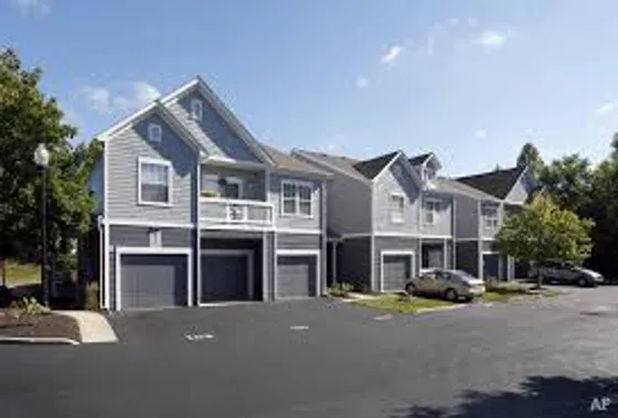 Charming apartment community with modern gray exteriors, balconies, and attached garages, set in a serene, tree-lined community.