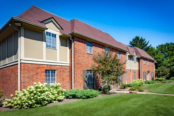 Charming brick apartment building with manicured lawns and vibrant greenery.
