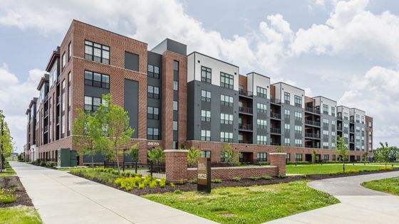 Modern apartment community with sleek brick and siding design, surrounded by lush landscaping and a welcoming entrance path.