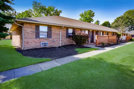 Charming brick apartment featuring lush landscaping and inviting private entryway in a serene neighborhood.
