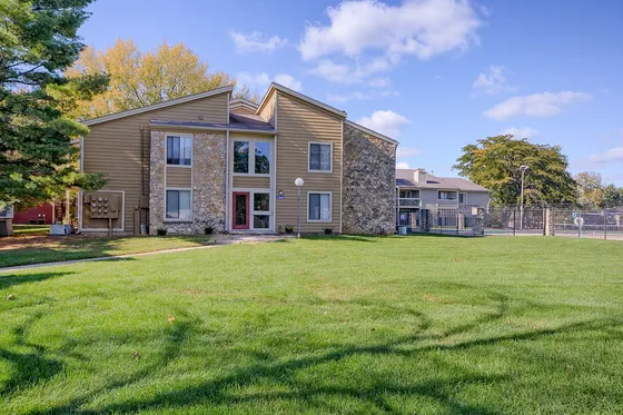 Charming apartment community with stone accents, large windows, and lush greenery.