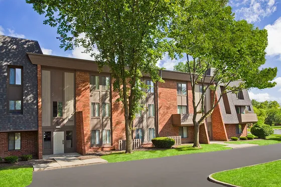 Charming apartment community with red brick exterior and lush green landscaping.