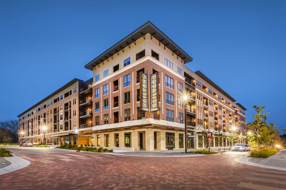 Elegant urban apartment complex with modern architecture and warm evening lighting, showcasing inviting balconies and vibrant street views.