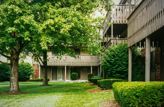 Charming apartment exterior with lush greenery, inviting balconies, and a serene garden setting.