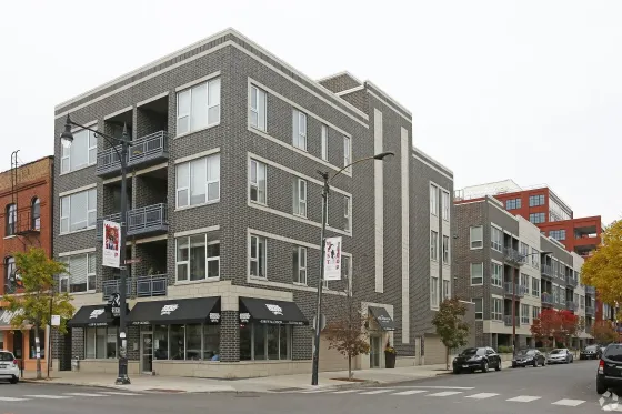 Modern urban apartment building with sleek design on a bustling city street, offering convenient access to local amenities.