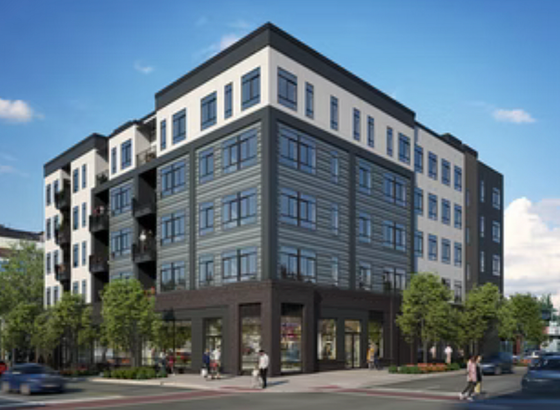 Modern five-story apartment building with large windows, balconies, and vibrant street-level shops surrounded by lush greenery.