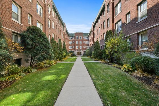 Charming brick apartment complex with lush greenery lining a central walkway, offering an inviting and peaceful atmosphere.