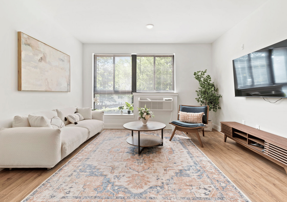 Bright living room with plush sofa, stylish armchair, and large windows facing a tranquil view.
