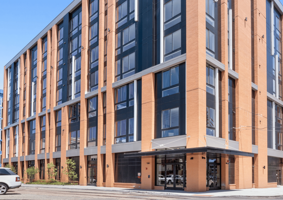 Modern brick apartment building with large windows and sleek design in an urban setting.
