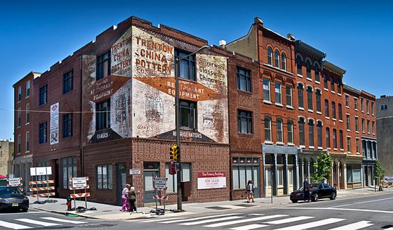 Street view of a charming historic brick building with vintage advertisements, featuring classic architectural details and a vibrant streetscape.