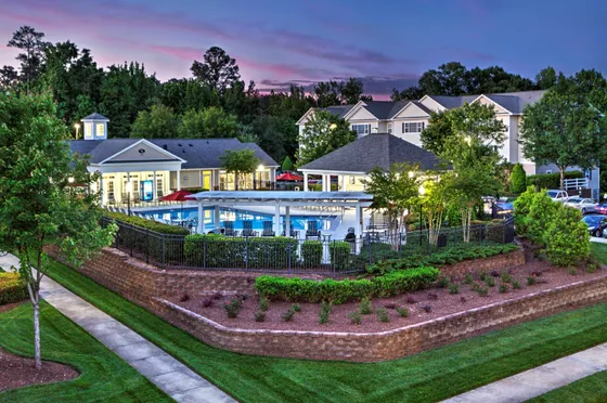 Luxurious apartment complex with a stunning illuminated swimming pool and stylish lounging area at dusk.