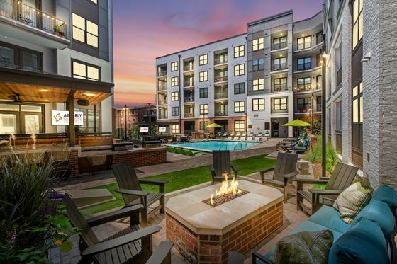 Luxurious apartment complex with a stunning illuminated swimming pool and stylish lounging area at dusk.