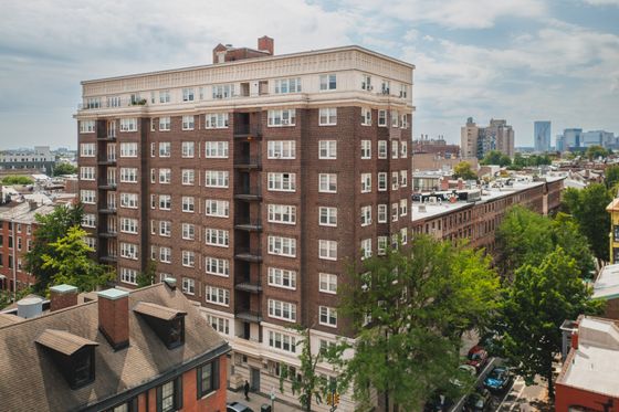 Charming urban apartment building showcasing classic architecture surrounded by lush greenery and city skyline views.