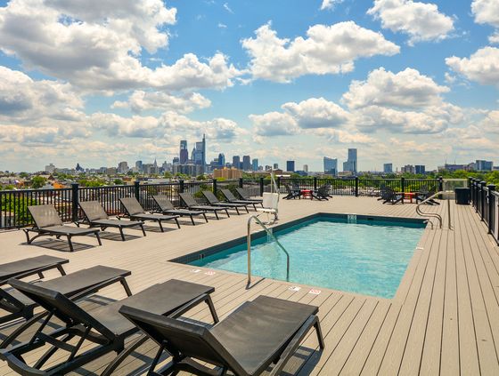 Luxurious rooftop pool with stunning city skyline view and ample lounge seating, perfect for relaxation.