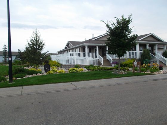 Charming residential property featuring expansive front porch, beautifully manicured gardens, and welcoming curb appeal.