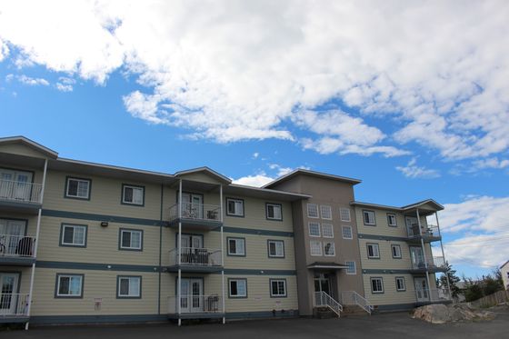 Charming three-story apartment building with cozy balconies, surrounded by a clear blue sky.
