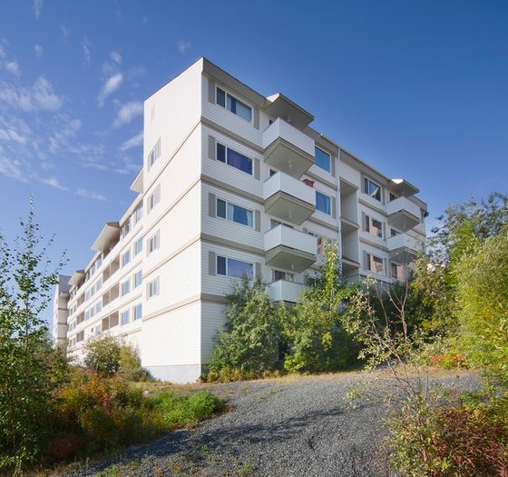Modern apartment building with sleek balconies and lush surroundings under a clear blue sky.