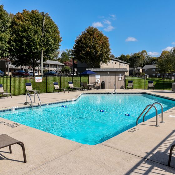 Inviting outdoor pool area surrounded by comfortable lounge chairs and lush greenery, perfect for relaxation and leisure.