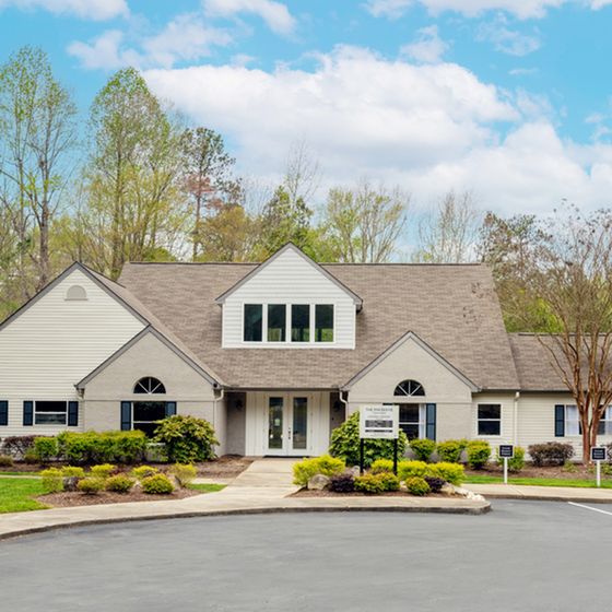 Charming residential building with elegant gabled roof, surrounded by lush greenery and a well-maintained driveway.
