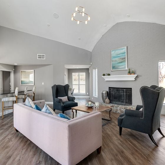 Bright and stylish living room with high ceilings, modern chandelier, and cozy seating by a charming fireplace.