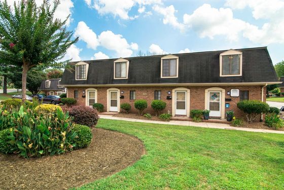 Charming townhouse exterior with manicured landscaping, lush greenery, and a bright, welcoming facade.