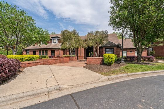 Charming brick apartment complex with lush landscaping and mature trees.