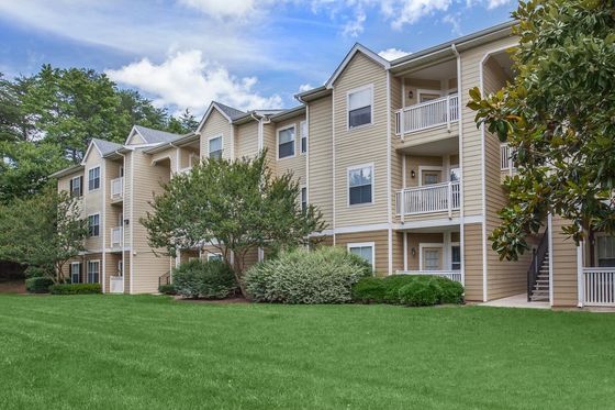 Charming apartment complex with inviting balconies and lush green landscaping, set against a vibrant blue sky.