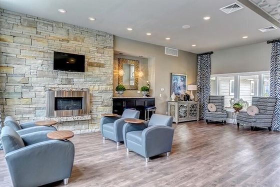 Spacious and elegant lounge area featuring modern seating, a stone fireplace, and abundant natural light ideal for relaxation.