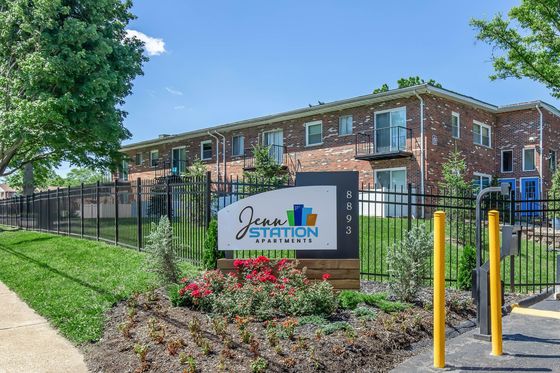 Delightful apartment building with a well-maintained garden and a welcoming sign, emphasizing a serene living environment.
