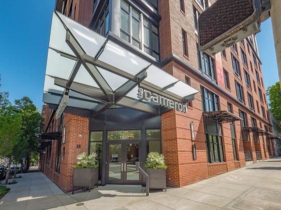 Chic urban apartment entrance with modern glass canopy at The Cameron, highlighting stylish city living.