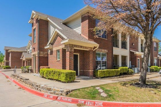 Charming red brick townhouse with modern architecture, surrounded by lush greenery and serene pathways.