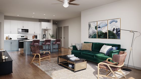 Modern open-concept living room with a plush green sofa, sleek kitchen island, and stylish decor, ideal for comfortable city living.