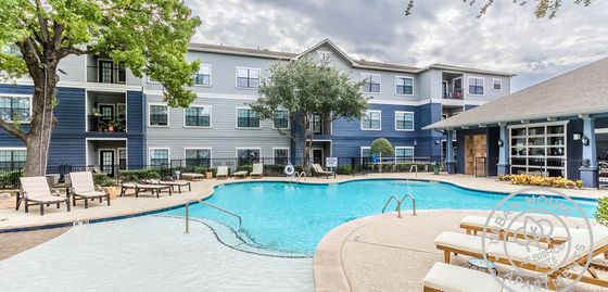 Inviting apartment complex with vibrant outdoor pool area, surrounded by lush greenery and comfortable lounge chairs, offering a relaxing atmosphere for residents.