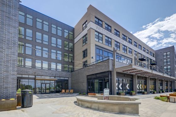 Modern urban apartment complex, Westminster Row, showcasing sleek architectural design with large windows, inviting courtyard, and stylish outdoor seating.