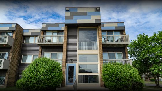 Chic, modern apartment building with vibrant architectural facade, private balconies, and lush greenery in a serene setting.