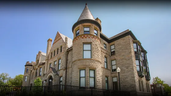 Elegant historic stone building with turret and arched entrance, featuring beautiful architectural details.